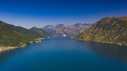 Scenic view of lake by mountains against clear blue sky