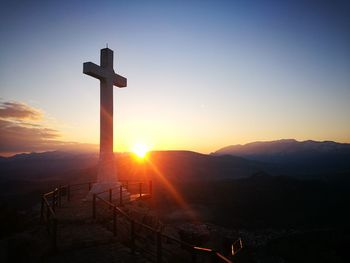 Silhouette cross against sky during sunset