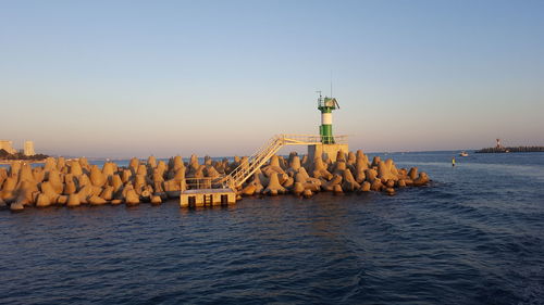 Lighthouse by sea against clear sky