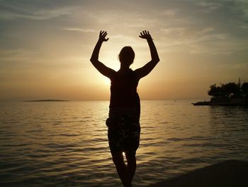 Silhouette of woman in sea at sunset
