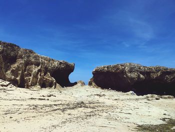 Rock formations on land against blue sky