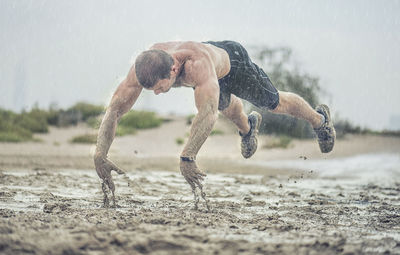 Close-up of athletic man exercising in mud during rainy season