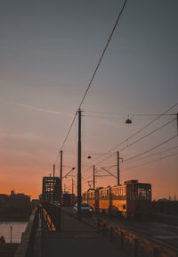 Bridge by buildings in city against sky during sunset