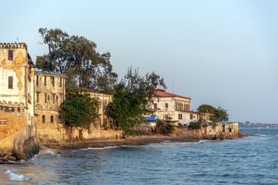 Houses by sea against sky in city