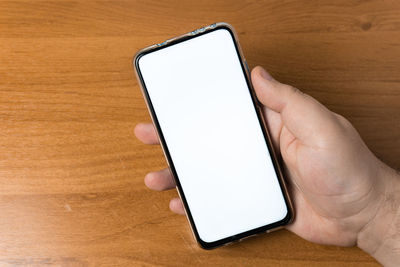 Low section of person holding smart phone on table