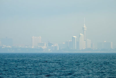 Sea by cityscape against sky