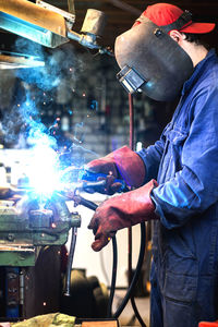 Side view of man welding in workshop