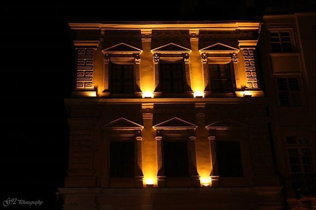 architecture, built structure, building exterior, illuminated, window, night, low angle view, orange color, building, no people, facade, lighting equipment, house, sunlight, outdoors, sunset, dark, brick wall, glowing, door