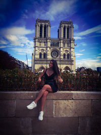 Full length of woman sitting against building