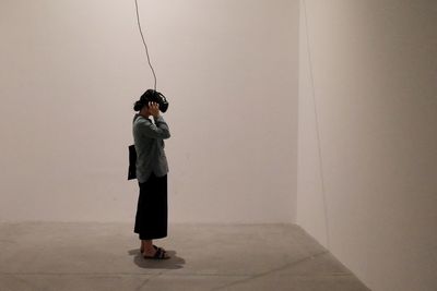 Full length of woman standing against wall