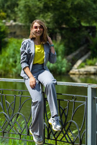 Portrait of woman siting on railing