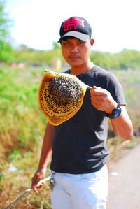 Portrait of mid adult man holding honeycomb with honey bees while standing outdoors