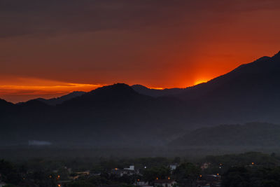 Scenic view of silhouette mountains against orange sky