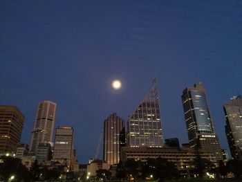 Illuminated modern buildings against clear sky at night