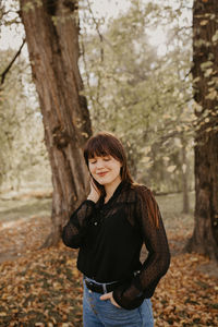 Young woman smiling while standing at park during autumn