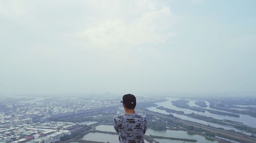 Rear view of woman standing on cityscape against sky