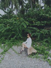 Portrait of woman standing by tree trunk