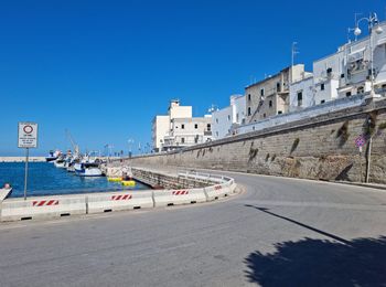 Road by buildings against clear blue sky