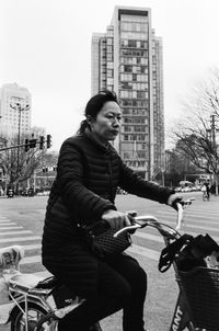 Young woman riding bicycle on city buildings