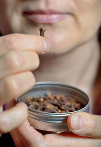 Close-up midsection of mature woman holding cloves in container