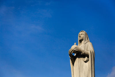 Low angle view of statue against blue sky