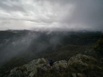 Rear view of man standing on mountain against sky