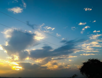 Low angle view of vapor trails in sky at sunset