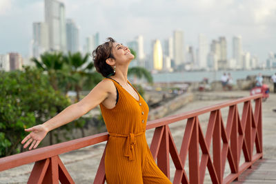 Side view of young woman standing by railing