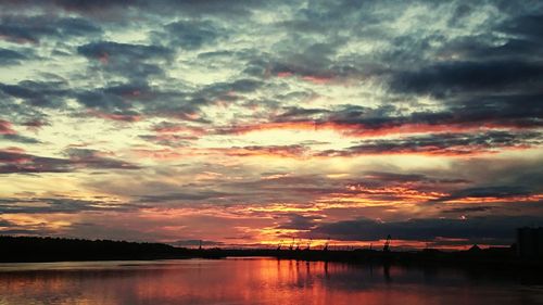 Scenic view of lake against dramatic sky during sunset