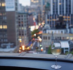 Close-up of champagne at window sill against cityscape