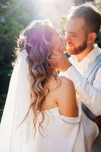 Newlywed couple embracing while standing outdoors