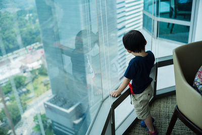 Rear view of man looking through window