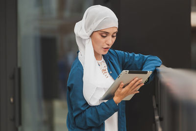 Smiling woman using digital tablet outdoors