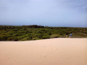 Man walking on sand dunes against sky