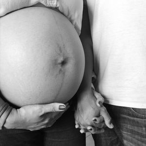 Midsection of pregnant woman holding hands