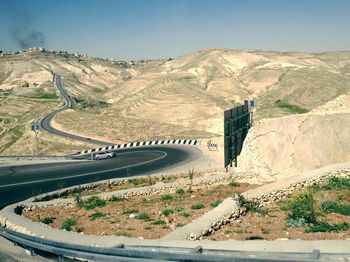 Scenic view of road by mountains against clear sky