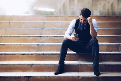Full length of young man sitting on staircase