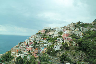 Positano on mountain by tyrrhenian sea against cloudy sky