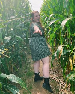 Midsection of woman standing amidst plants in field