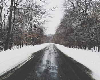 Snow covered road passing through trees