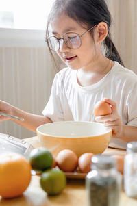 Girl reading book while preparing food at home
