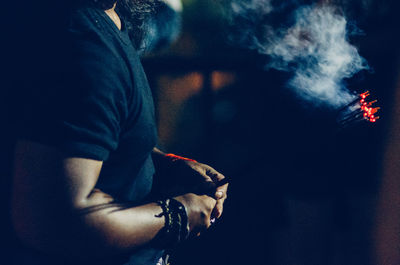 Midsection of man with incenses at temple