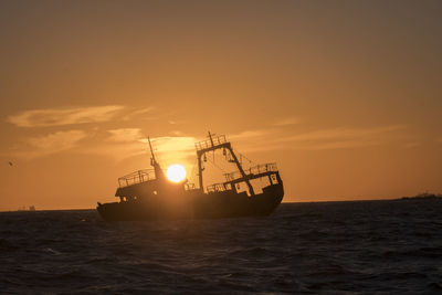 Ship wrecks at beachside at sunrise in backlight