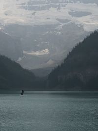 Man paddle boarding in lake against mountain