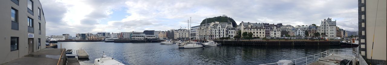 Panoramic view of boats moored at harbor against sky in city