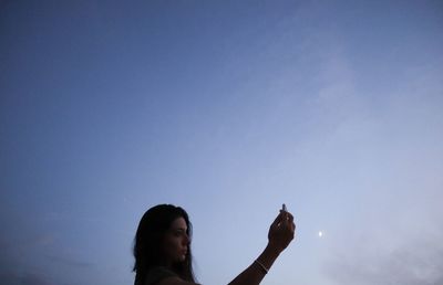 Low angle view of woman against blue sky