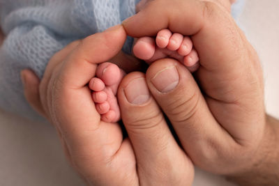 Cropped hand of man holding baby's leg