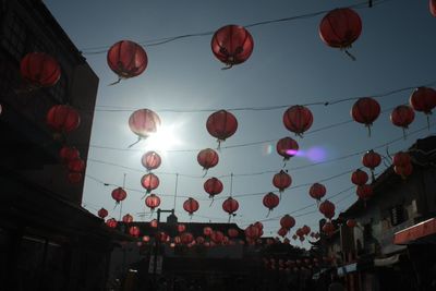 Low angle view of lanterns hanging amidst buildings against sky