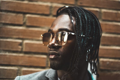 Portrait of young man wearing eyeglasses against wall