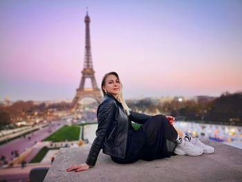 Portrait of woman in city against sky during sunset